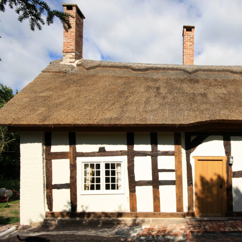 Listed building with oak frame and render infill panels which have been insulated and thatched roof